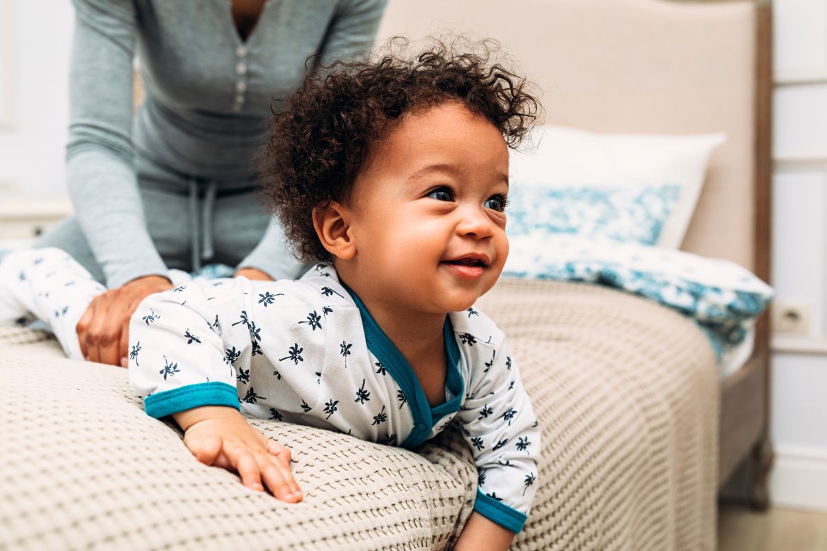 Bébé garçon avec des cheveux bouclés jouant sur un lit