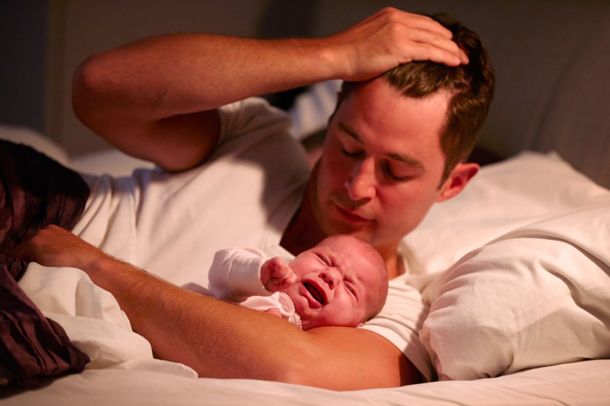 Père réconfortant son bébé en pleurs pendant un réveil nocturne